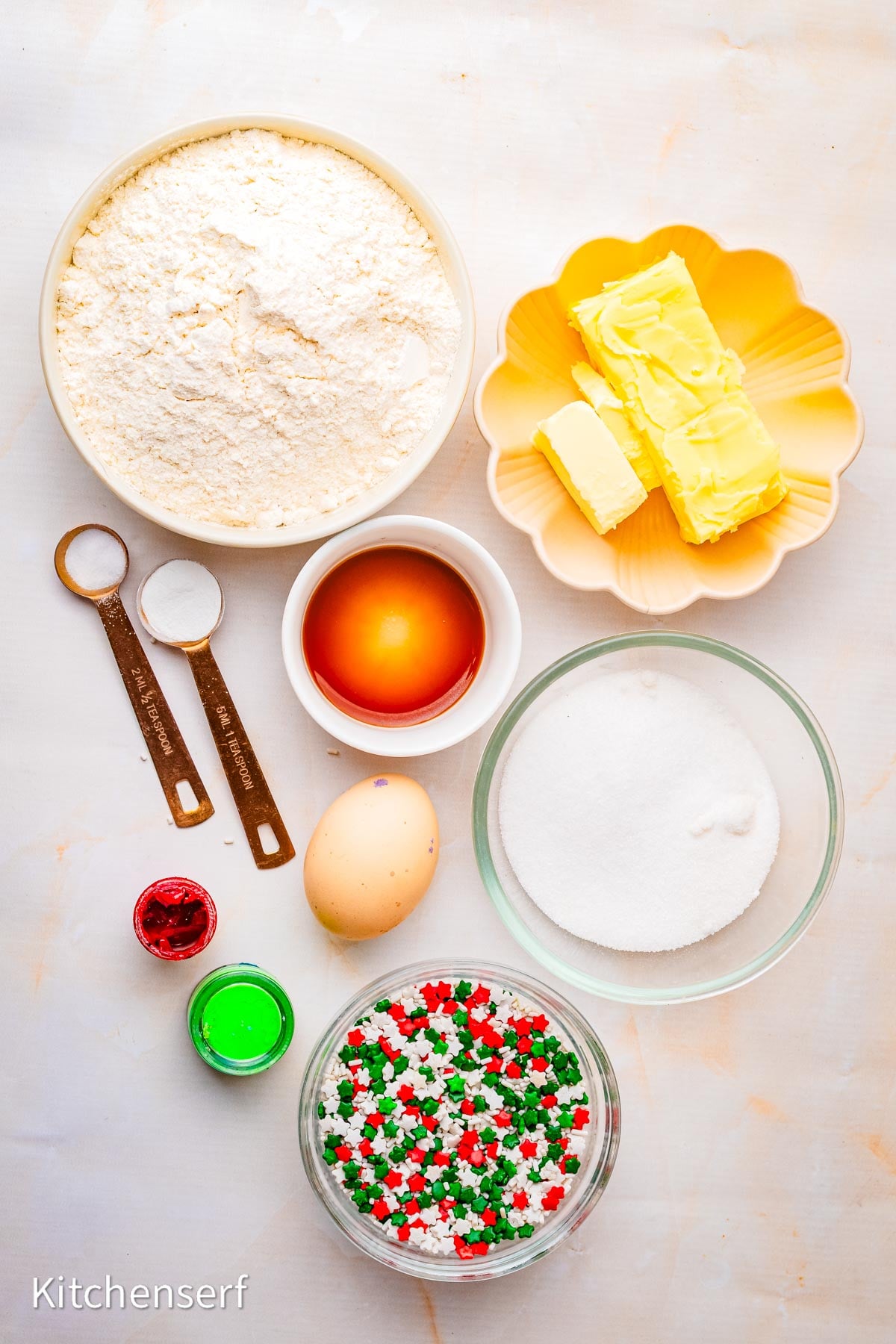 Bowls with flour, sugar, butter, egg, vanilla, baking soda, salt, food coloring, and Christmas sprinkles—everything you need to make peppermint pinwheel cookies.