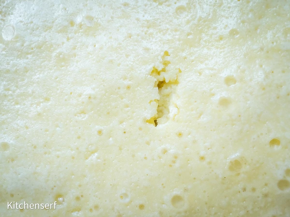 Close-up of a bubbly, spongy St. Louis gooey butter cake surface with a small crack in the center.