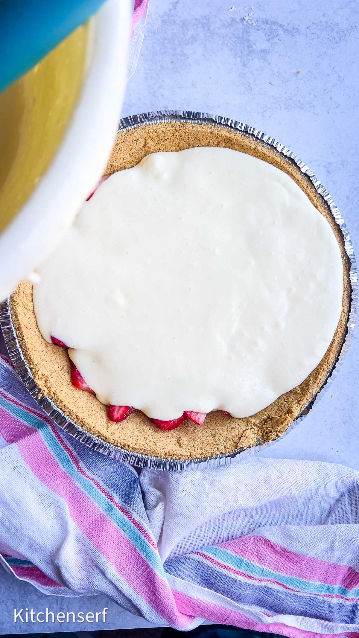 A graham cracker pie crust filled with fresh strawberries and topped with a creamy white mixture, creating a  strawberry cheesecake-inspired treat.