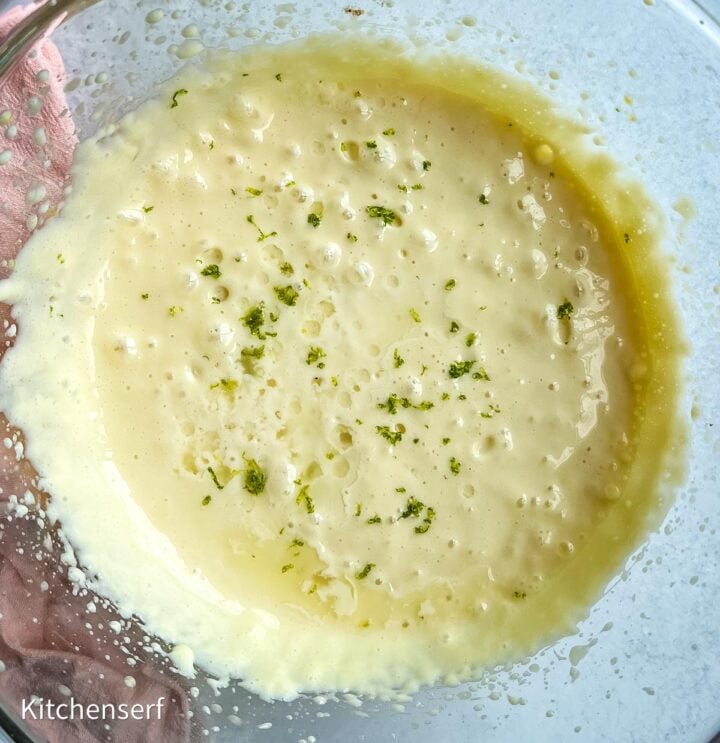Creamy yellow mixture in a glass bowl, topped with small flecks of green zest, reminiscent of easy Nellie & Joe's Key Lime Pie.