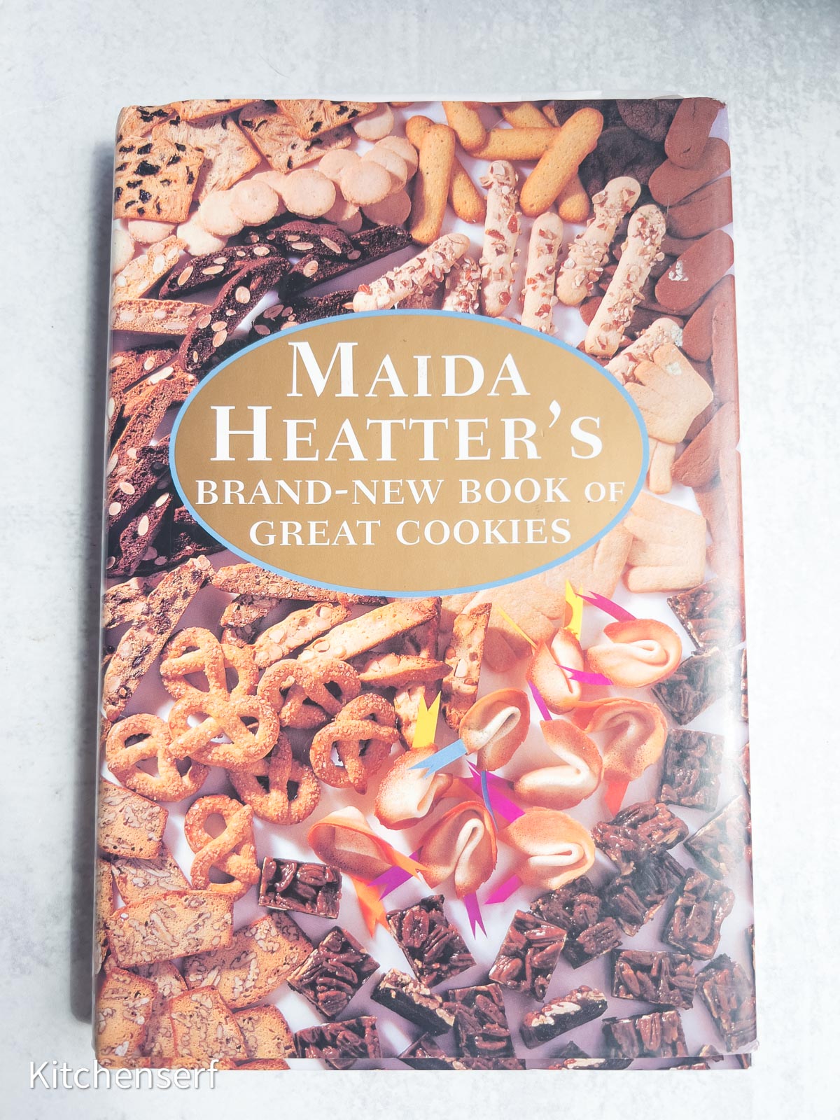 A cookbook titled Maida Heatter’s Brand-New Book of Great Cookies, featuring cookies on the cover, is a delightful addition to any collection of baking books.