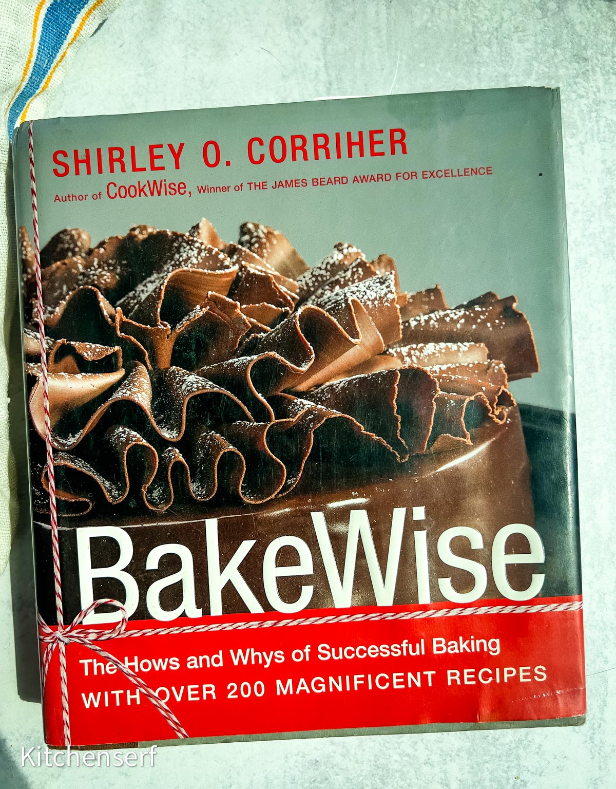 BakeWise cookbook cover featuring a close-up of a chocolate cake with ruffled frosting and powdered sugar, capturing the irresistible appeal of beloved baking books.