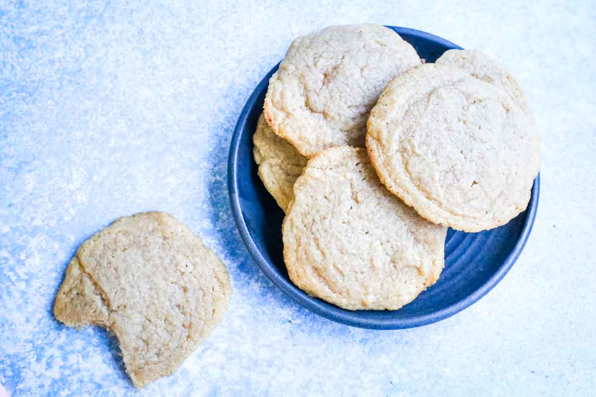 chocolate shipless cookies on a blue background laying on a teal plate with one to the side.
