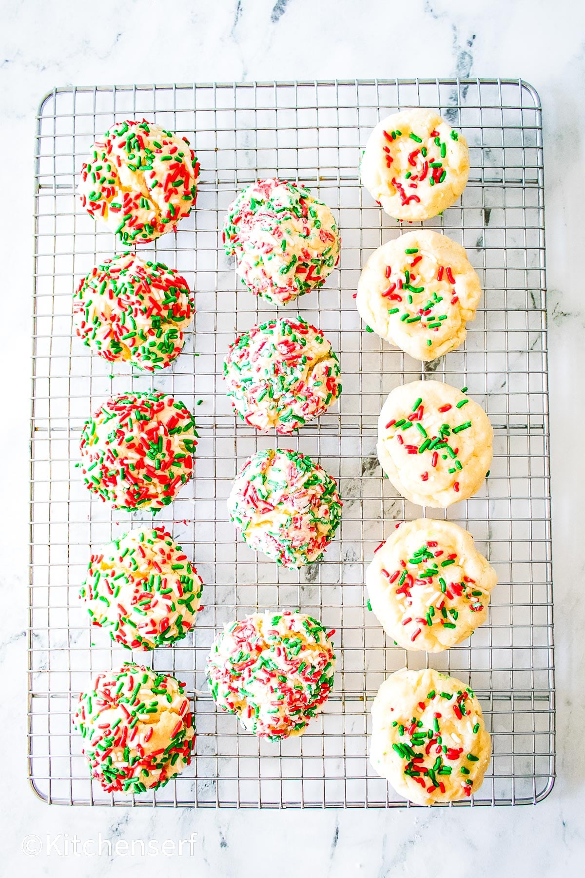 Twelve round cookies with red and green sprinkles on a wire cooling rack, seen from above.