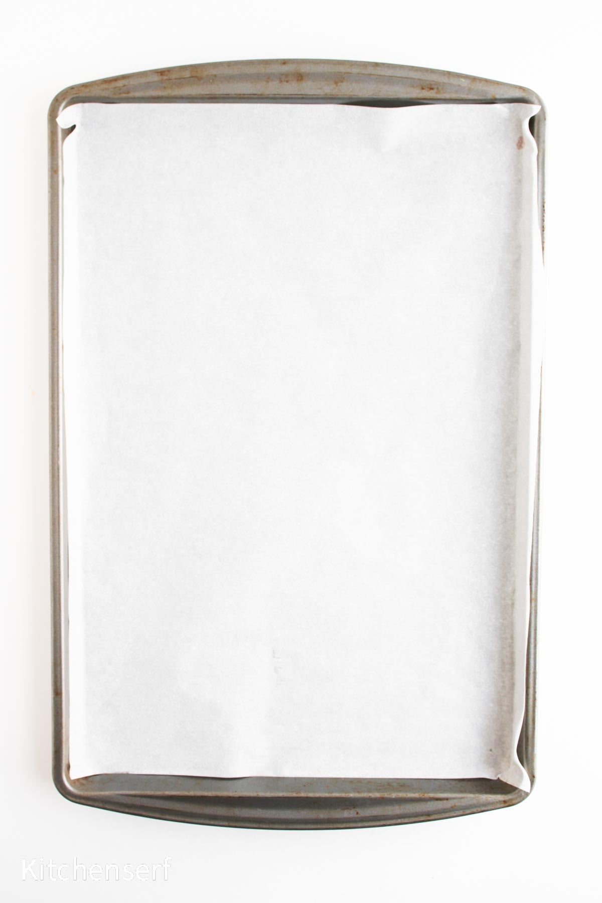 A baking sheet lined with white parchment paper on a white background.