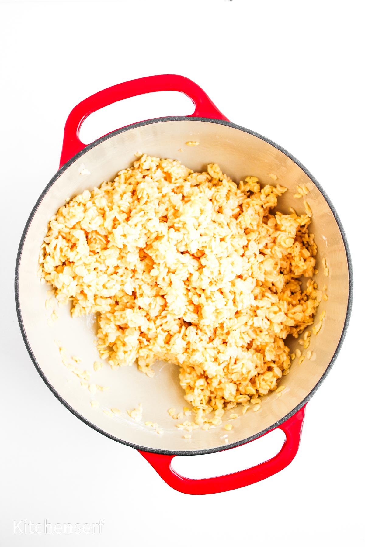 A red pot filled with cooked scrambled eggs on a white background.