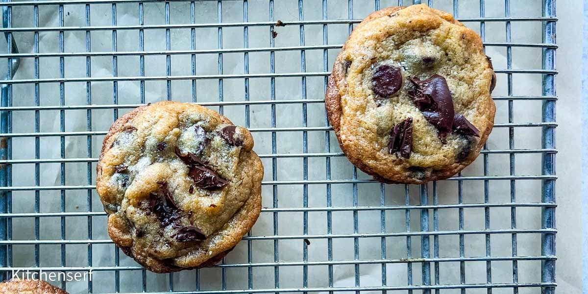 Two chocolate chip cookies with vanilla pudding cool on a metal wire rack.