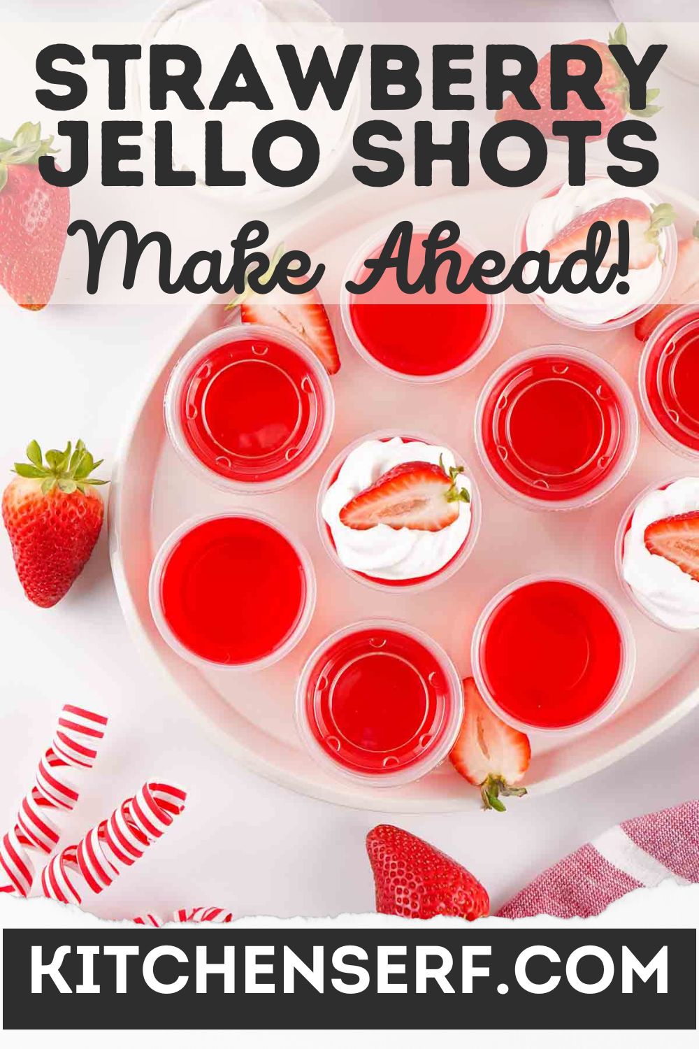 Red strawberry jello shots in cups, topped with sliced strawberries and surrounded by fresh berries..