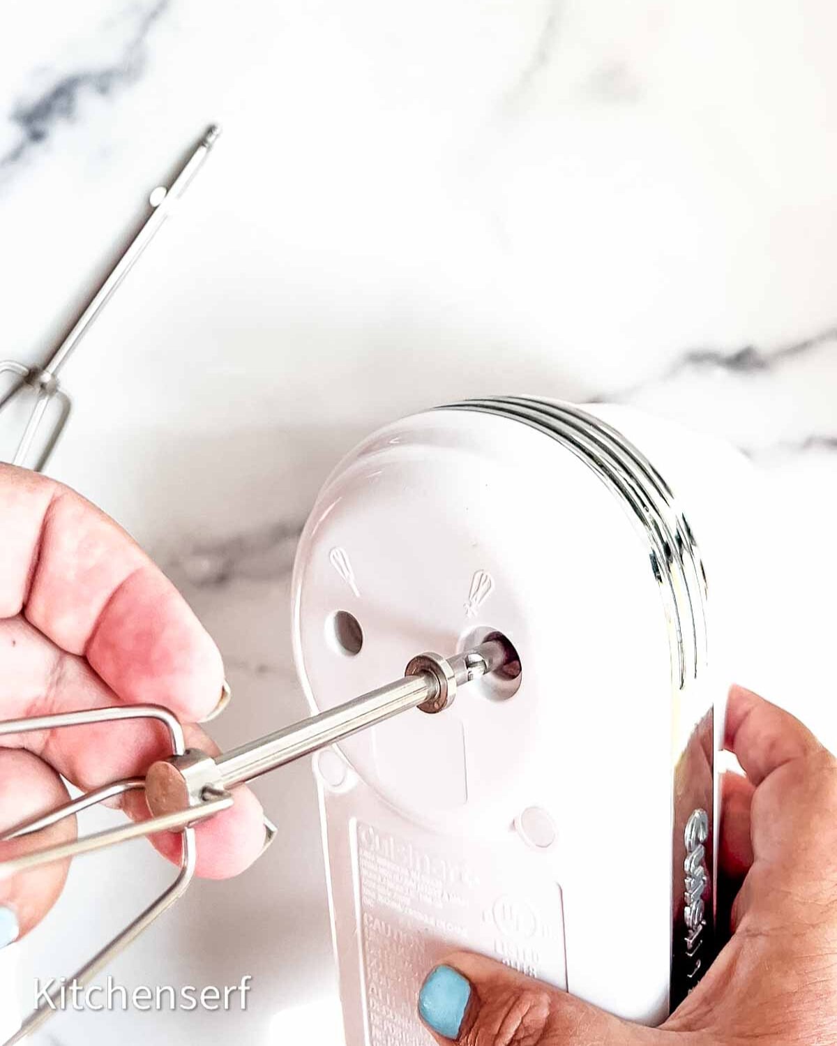 back of a hand mixer being held and a beater being inserted.