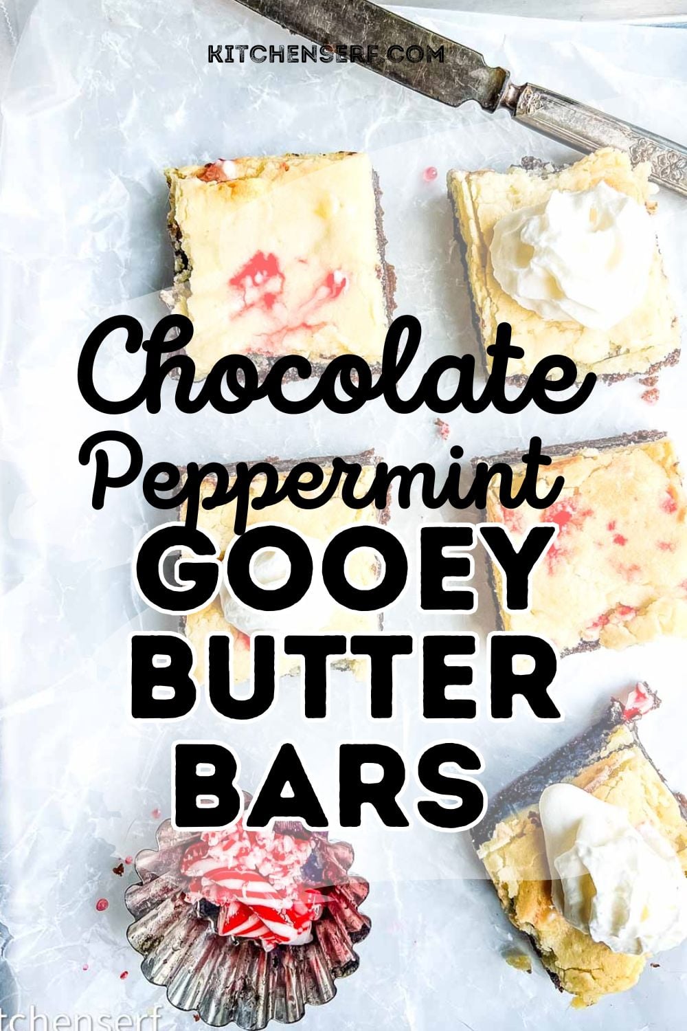 Top-down view of chocolate peppermint gooey butter bars topped with whipped cream and crushed candy canes on parchment paper.