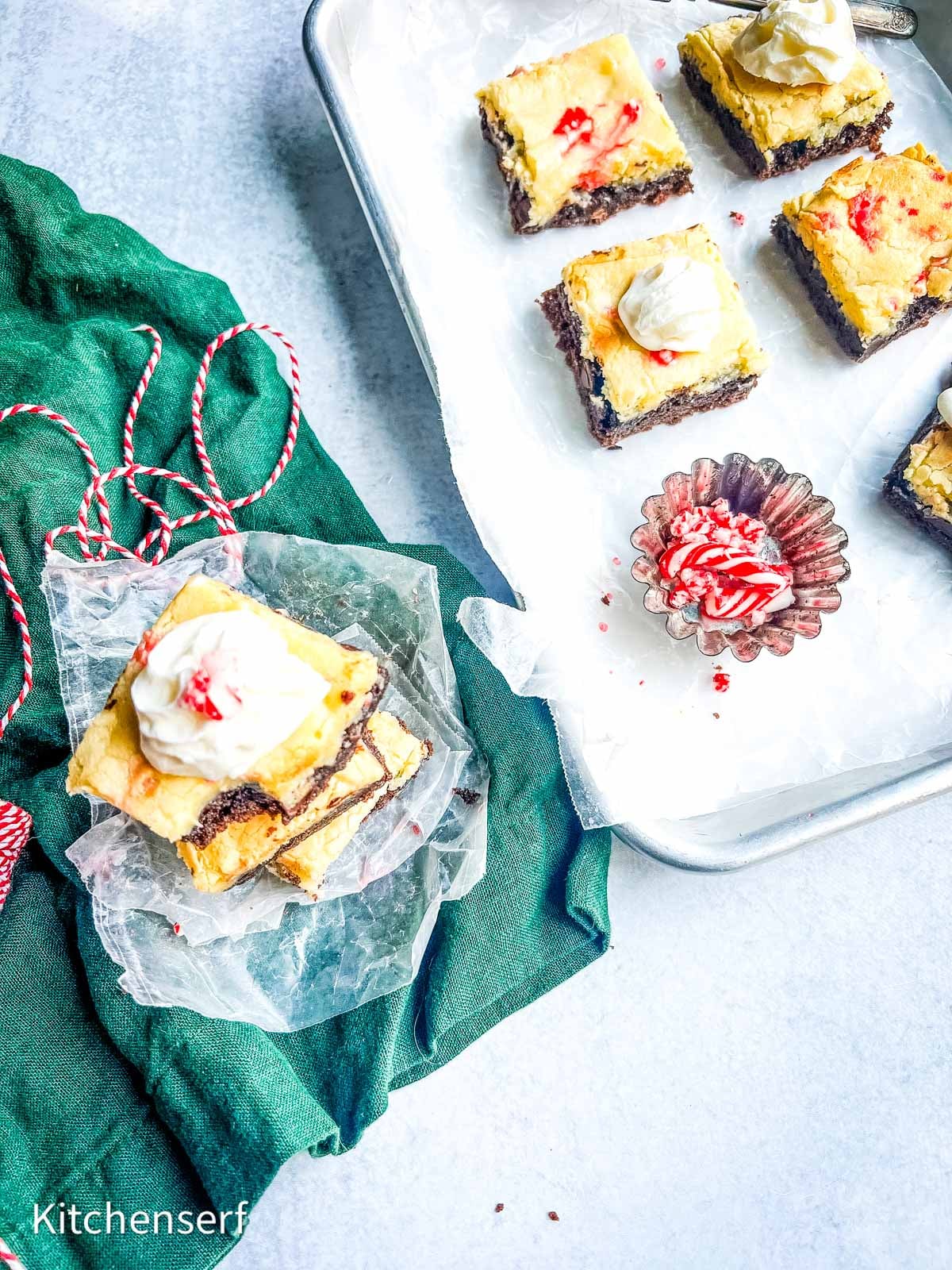 chocolate peppermint gooey butter cake bars on a tray with a stack on wax paper on a green  linen napkin.