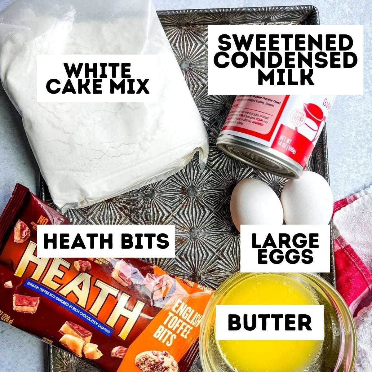 Baking ingredients on a tray: white cake mix, sweetened condensed milk, Heath bits, eggs, and melted butter.