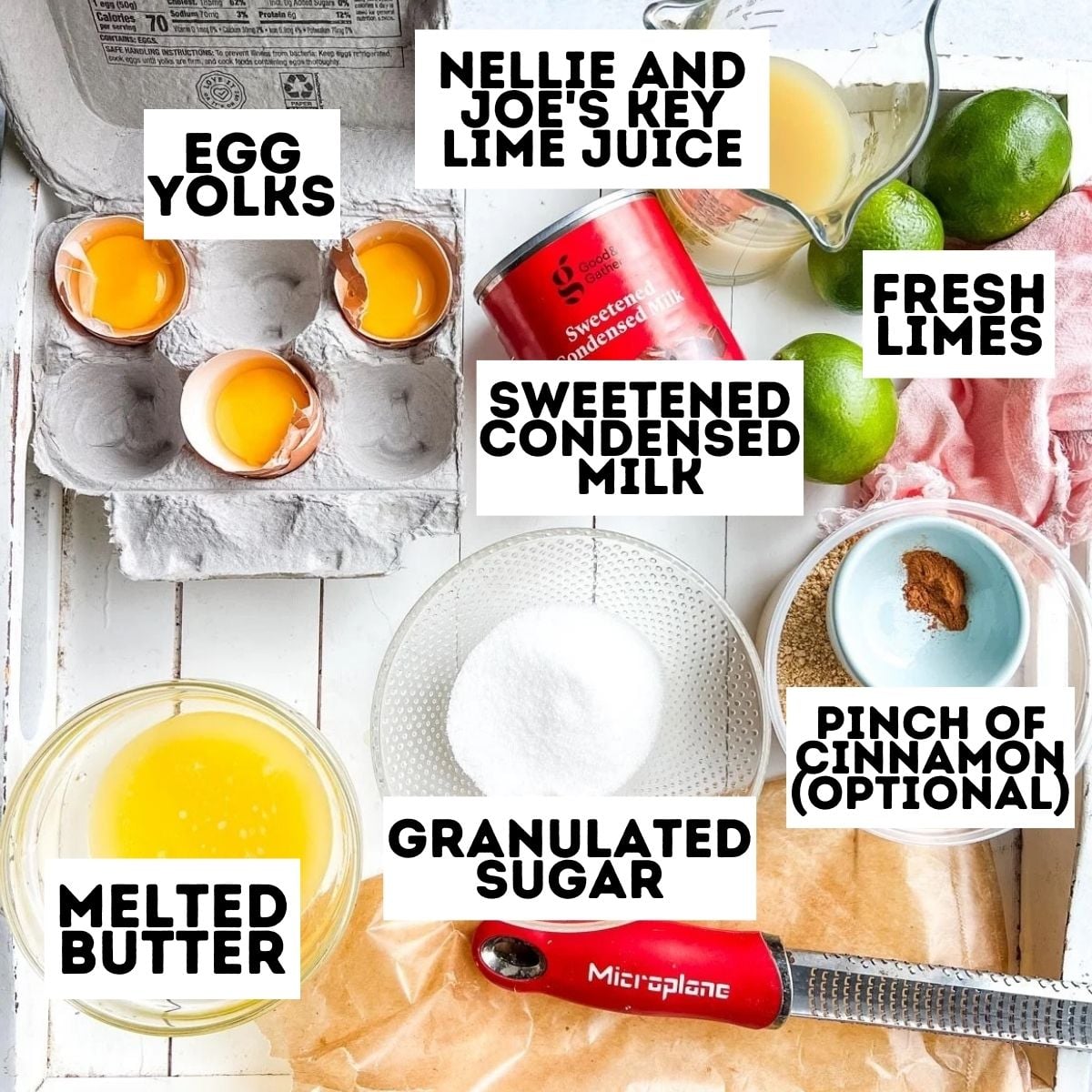 Ingredients for key lime pie, labeled: egg yolks, lime juice, condensed milk, limes, cinnamon, sugar, butter.