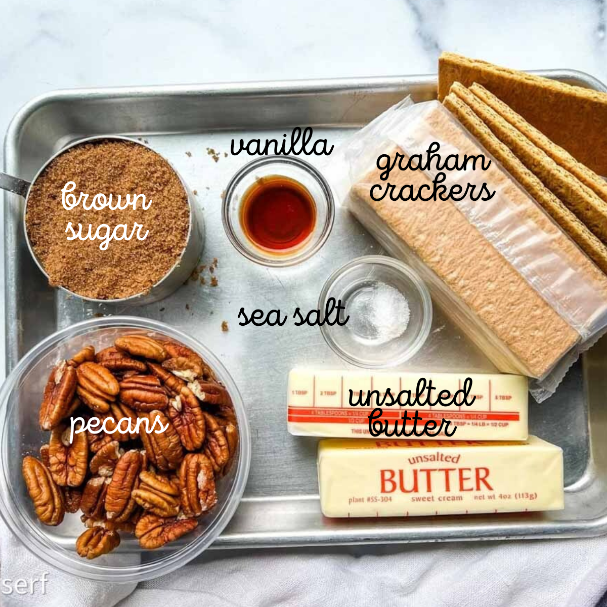 A tray with pecans, brown sugar, vanilla, sea salt, unsalted butter, and graham crackers.