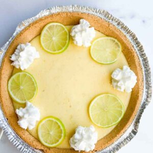 Key lime pie with a graham cracker crust, topped with lime slices and dollops of whipped cream.