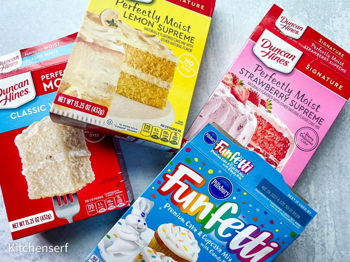 Four colorful cake mix boxes, including Funfetti, arranged on a light blue surface—perfect for whipping up delicious cake mix cookies.
