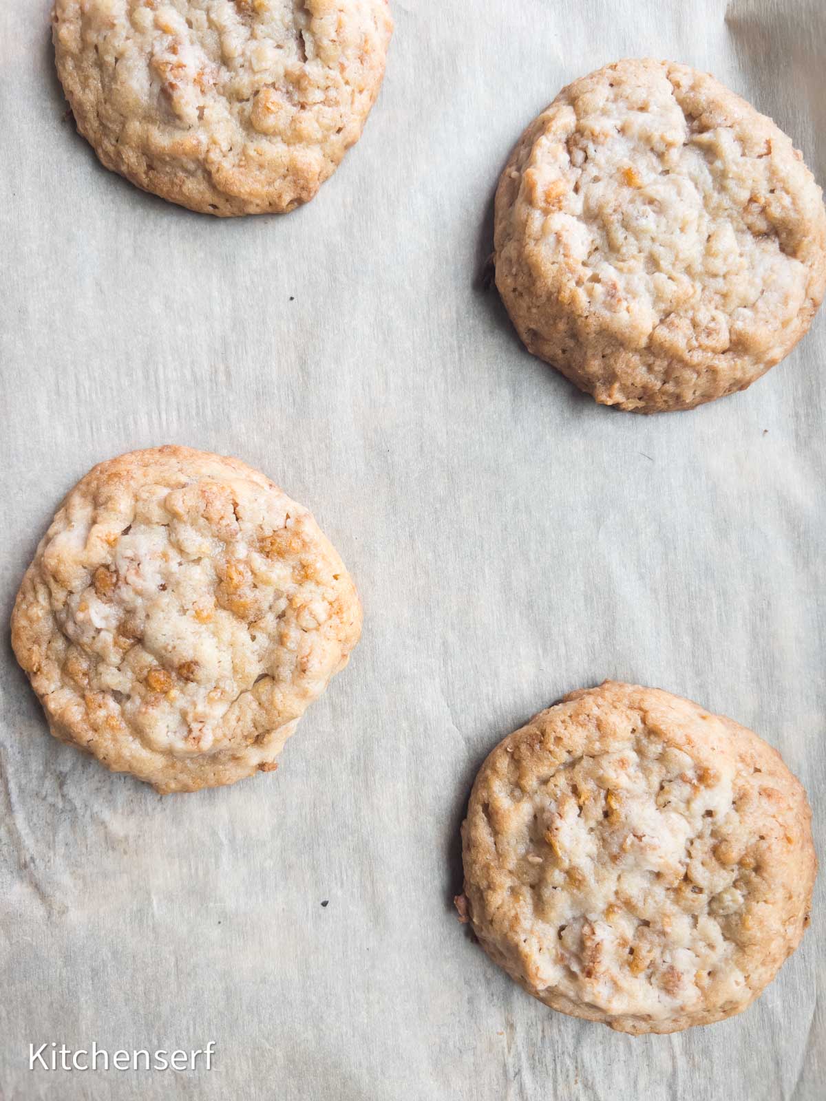 Four homemade cookies on a baking sheet lined with parchment paper.