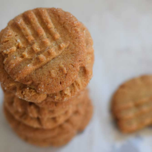 Stack of peanut butter cookies with fork marks on top, one cookie lying next to the stack.