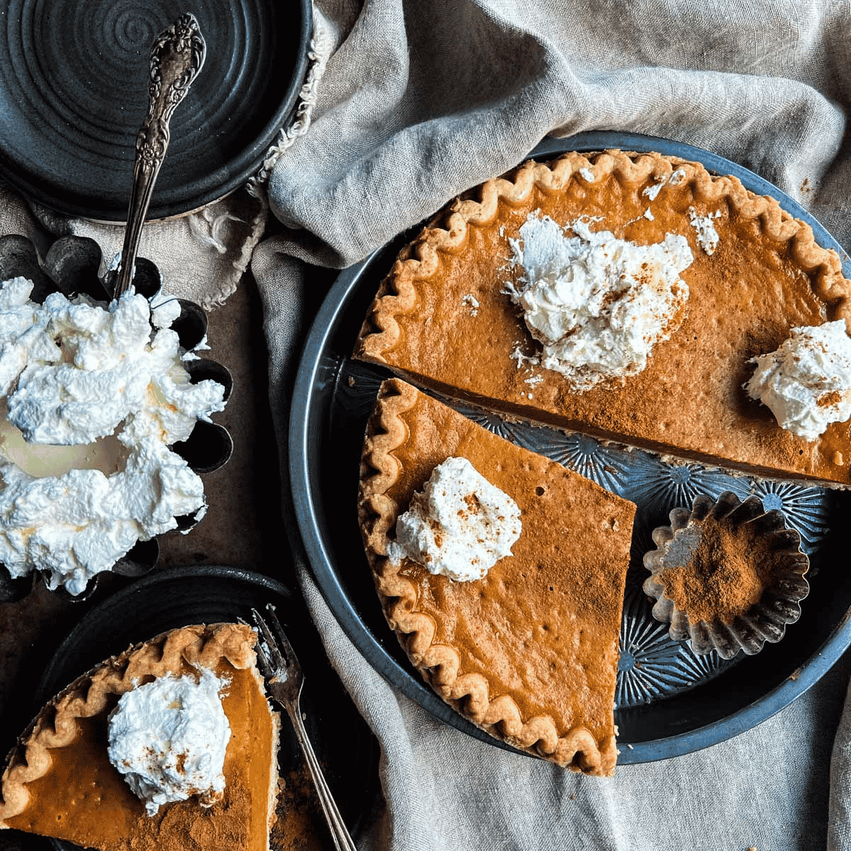 Pumpkin pie with whipped cream on top, a slice served on a plate, and extra whipped cream nearby—perfect for fall baking.