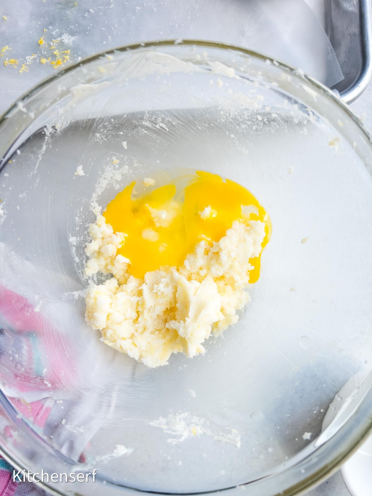 Egg yolks and creamed sugar in a glass mixing bowl, ready to be mixed for baking delicious soft lemon sugar cookies.