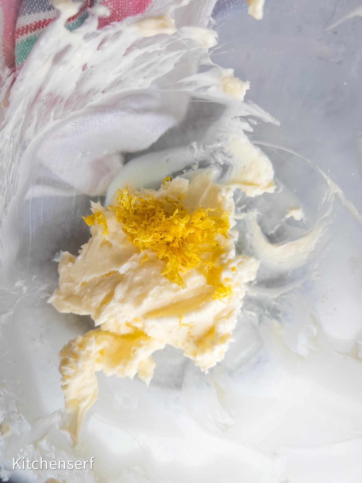 Butter and lemon zest in a mixing bowl, ready to create soft lemon sugar cookies, with a striped cloth in the background.